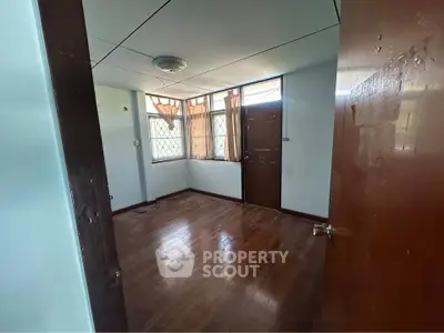 Spacious empty room with wooden floors and large windows, ideal for customization.