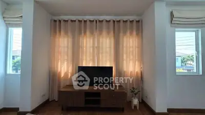 Cozy living room with TV stand and elegant curtains, perfect for relaxation.