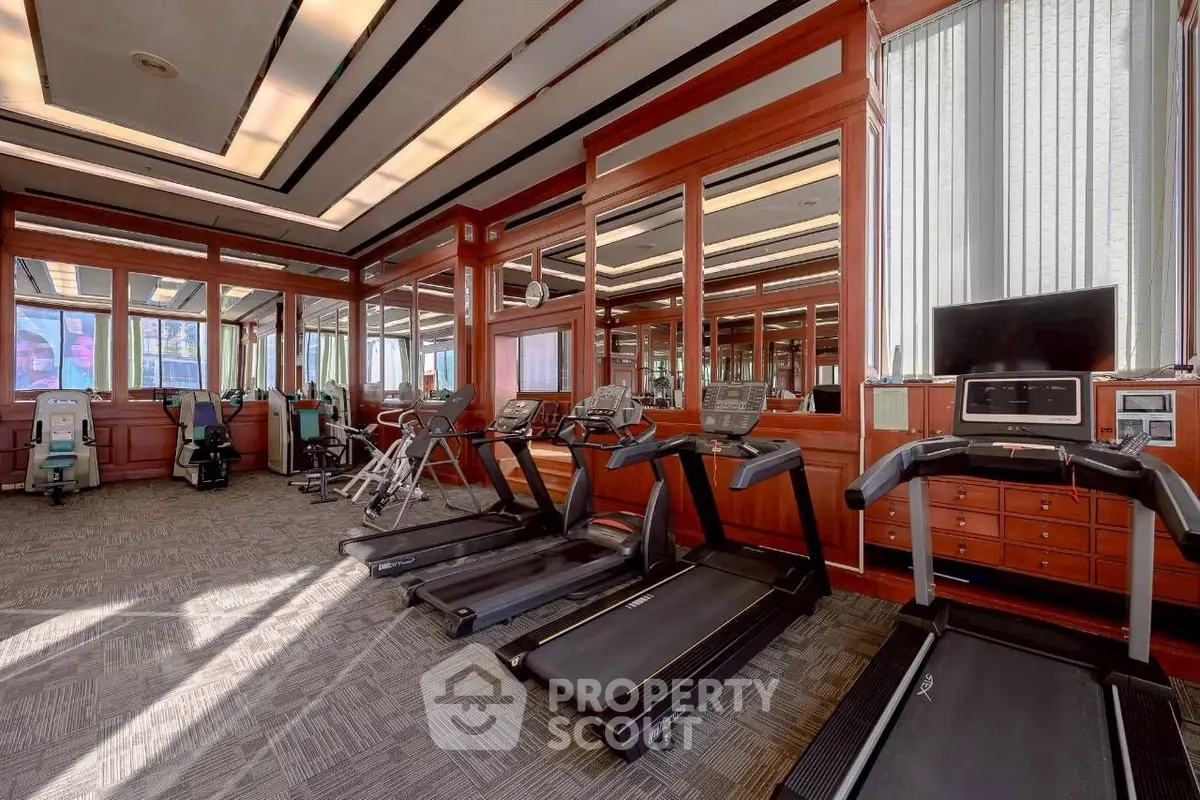 Luxurious gym with modern equipment and elegant wood paneling in upscale residential building.