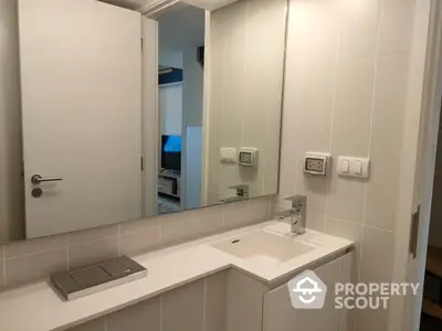 Sleek white bathroom vanity with modern fixtures and large mirror, reflecting a glimpse of a cozy interior space, ideal for urban living.