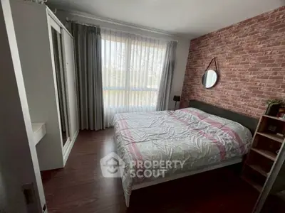 Cozy bedroom with brick accent wall and large window for natural light.