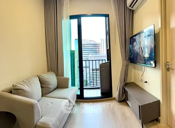 Modern living room with balcony and city view, featuring a cozy sofa and wall-mounted TV.
