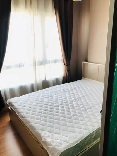 Cozy bedroom with natural light and elegant curtains, perfect for relaxation and comfort.