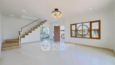 Spacious modern living room with elegant staircase and large windows.