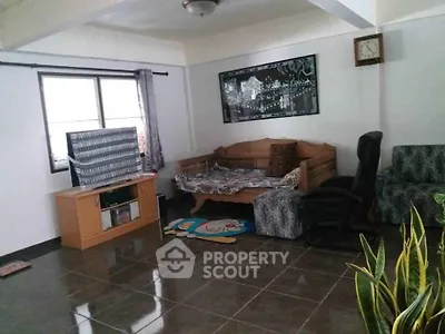 Spacious living room with tiled floor, cozy seating, and natural light from large window.