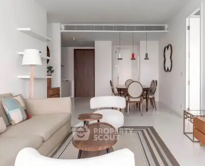 Modern living room with stylish furniture and open dining area, featuring elegant decor and neutral tones.
