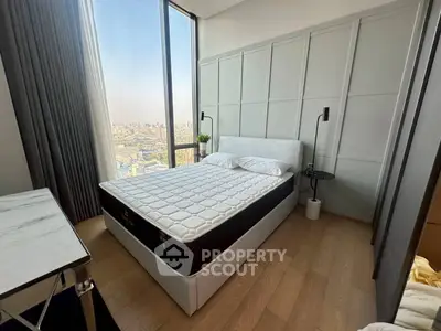 Modern bedroom with large window offering stunning city view, featuring elegant decor and cozy ambiance.