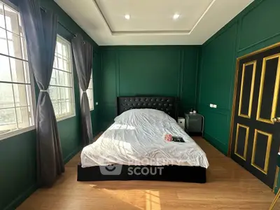 Luxurious bedroom with elegant green walls and large windows offering natural light.