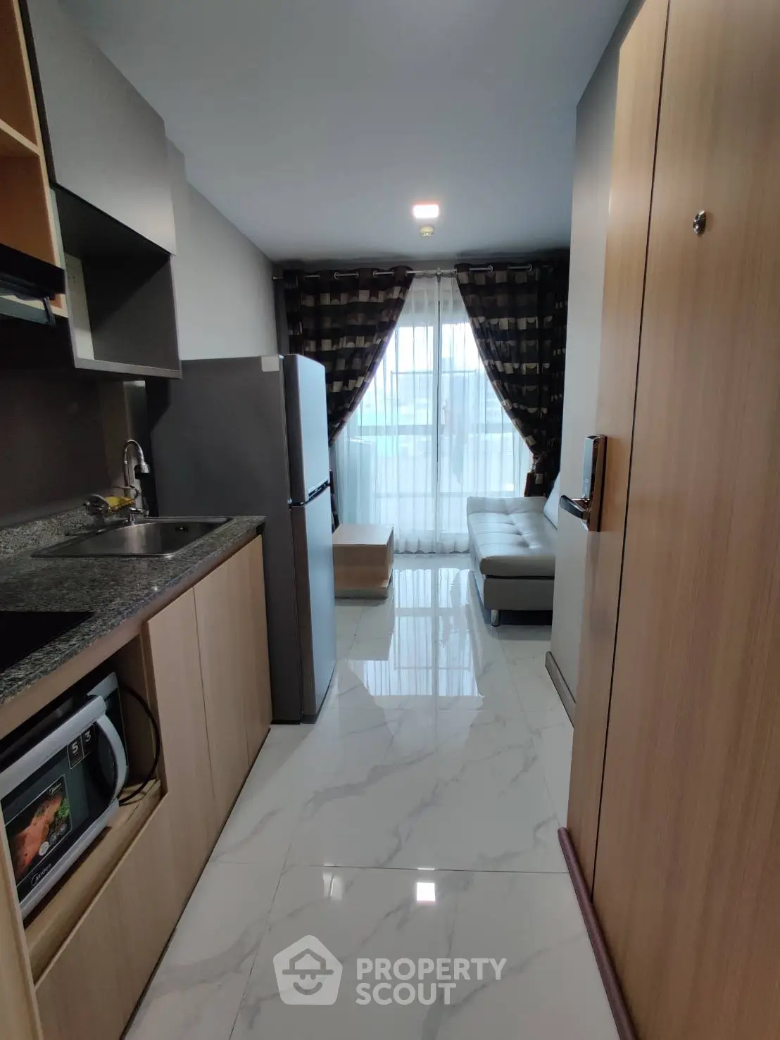 Modern apartment kitchen with sleek design and open layout leading to a cozy living area.