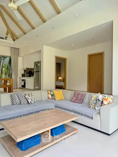 Spacious living room with modern decor and open kitchen layout, featuring cozy seating and stylish design.