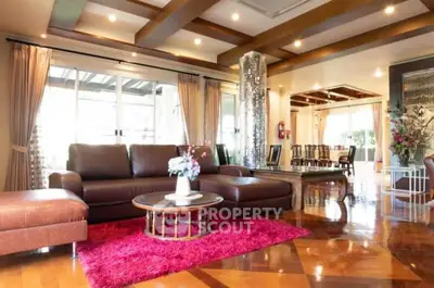 Luxurious living room with elegant decor and spacious layout, featuring leather sofas and vibrant red rug.