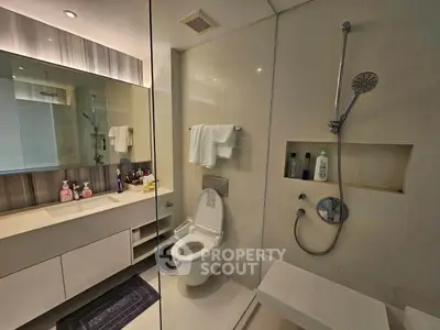 Modern bathroom with sleek fixtures and glass shower enclosure in luxury apartment.