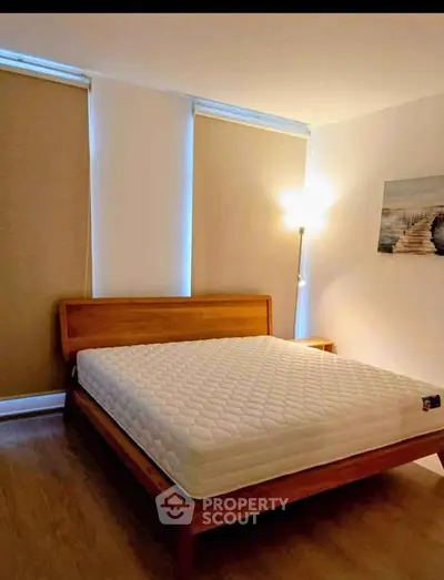Cozy bedroom with wooden bed frame and soft lighting, perfect for relaxation.
