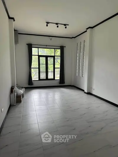 Spacious empty room with large window and elegant tile flooring