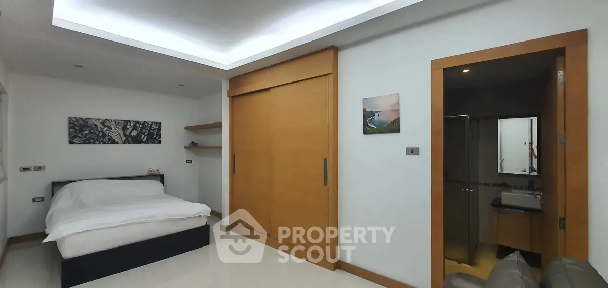 Modern bedroom with sleek design and ensuite bathroom in a contemporary home.