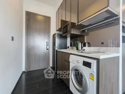 Modern kitchen with sleek appliances and washing machine in compact layout.