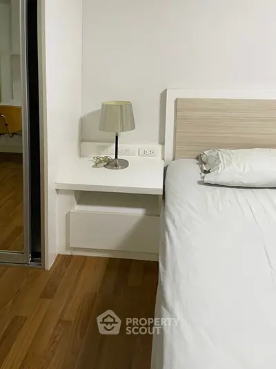 Modern bedroom with sleek wooden flooring and minimalist bedside table.