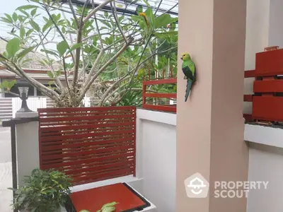 Charming garden view with vibrant parrot and modern red accents in serene residential setting.