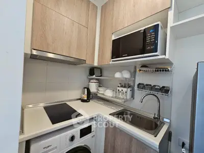 Modern compact kitchen with wooden cabinets, microwave, and washing machine