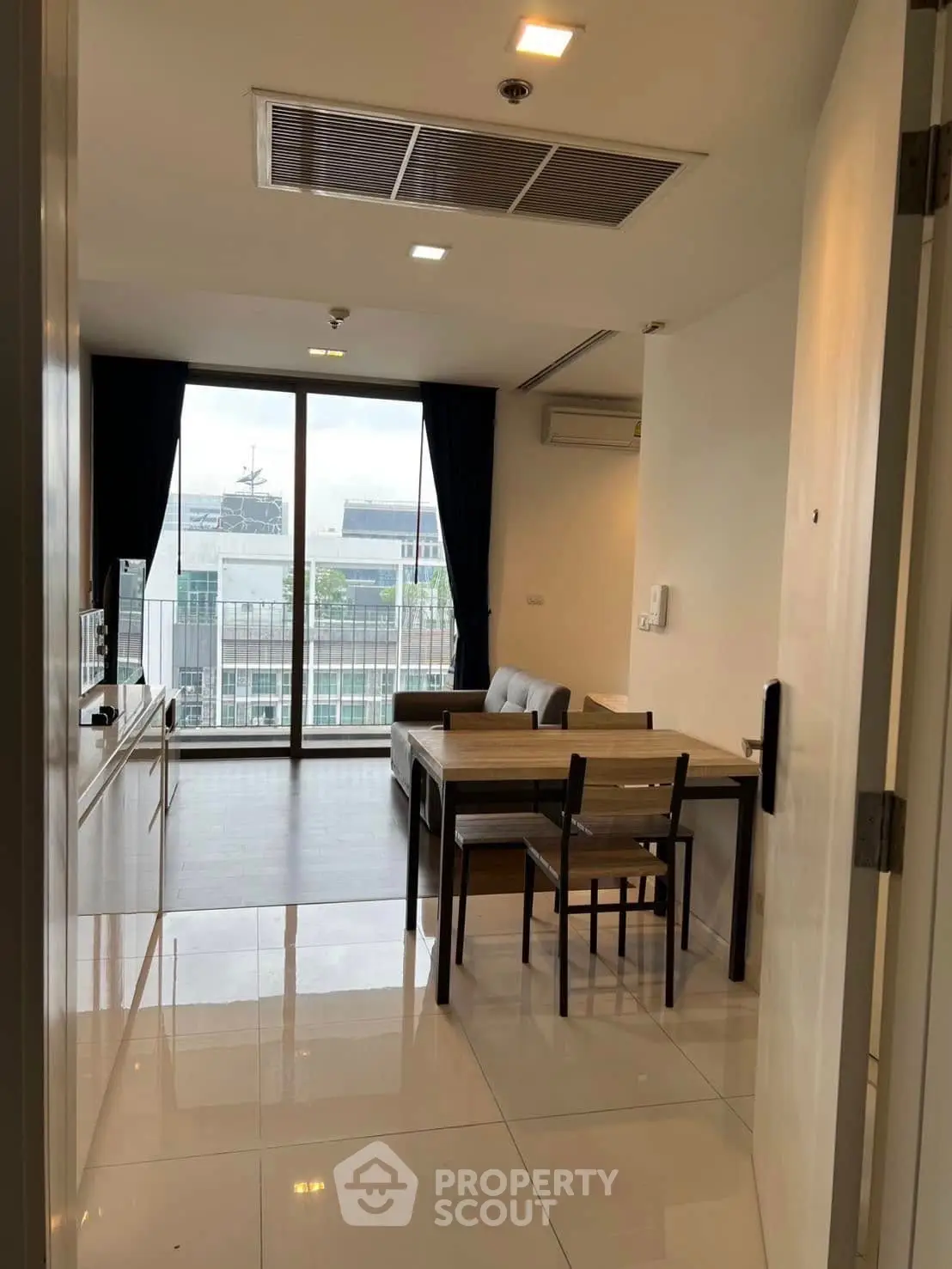 Modern apartment living room with dining area and large windows offering city views.