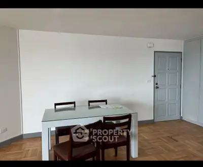 Minimalist dining area with wooden chairs and table on parquet flooring.