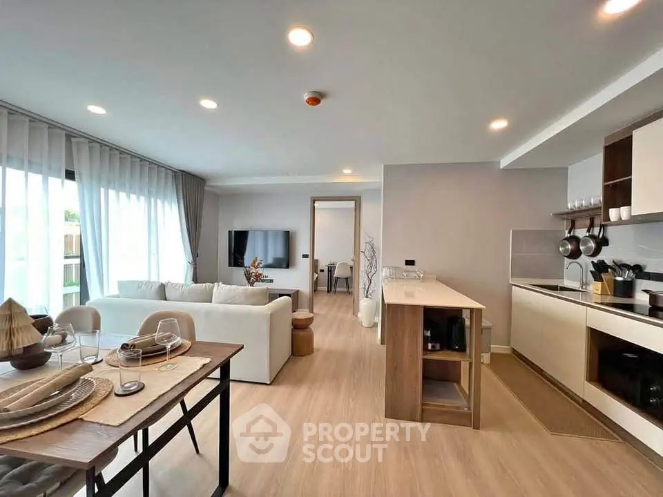 Modern open-plan living room and kitchen with elegant decor and natural light.