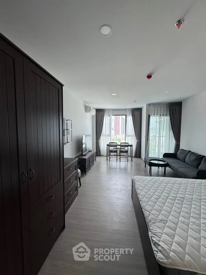 Spacious modern studio apartment with stylish furniture and large windows offering natural light.