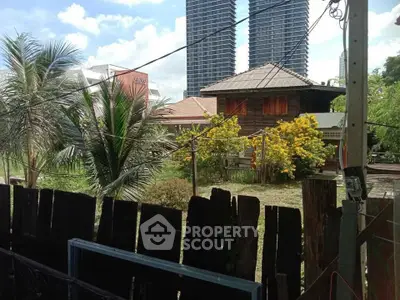Charming rustic house with lush garden and modern skyscrapers in the background, offering a unique urban-rural blend.