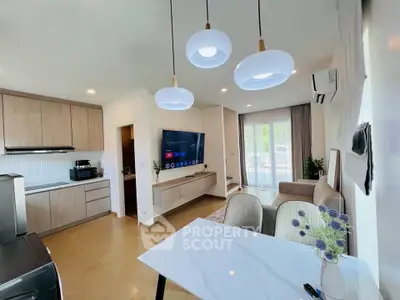 Modern open-plan living room with stylish kitchen and elegant dining area, featuring contemporary lighting and decor.