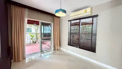 Spacious living room with large windows and access to a private balcony, featuring modern lighting and air conditioning.
