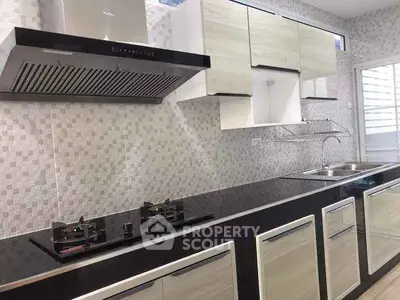 Modern kitchen with sleek cabinets and gas stove, featuring a stylish backsplash and dual sinks.