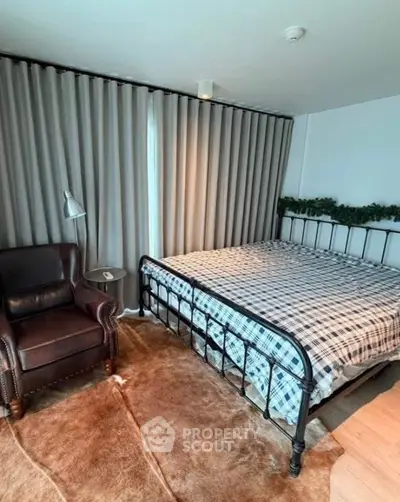 Cozy bedroom with metal bed frame, leather armchair, and floor-to-ceiling curtains.
