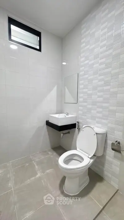 Modern minimalist bathroom with sleek white tiles and contemporary fixtures.