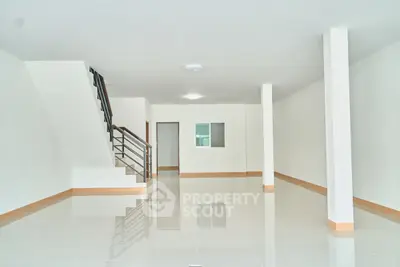 Spacious open-plan interior with sleek staircase and glossy tiled flooring, ideal for modern living.
