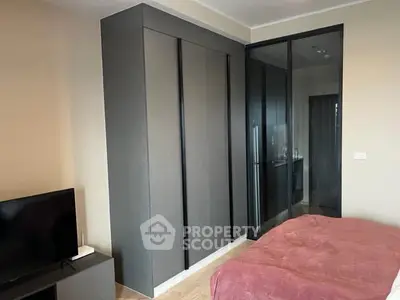 Modern bedroom with sleek wardrobe and glass partition, featuring a cozy bed and TV setup.