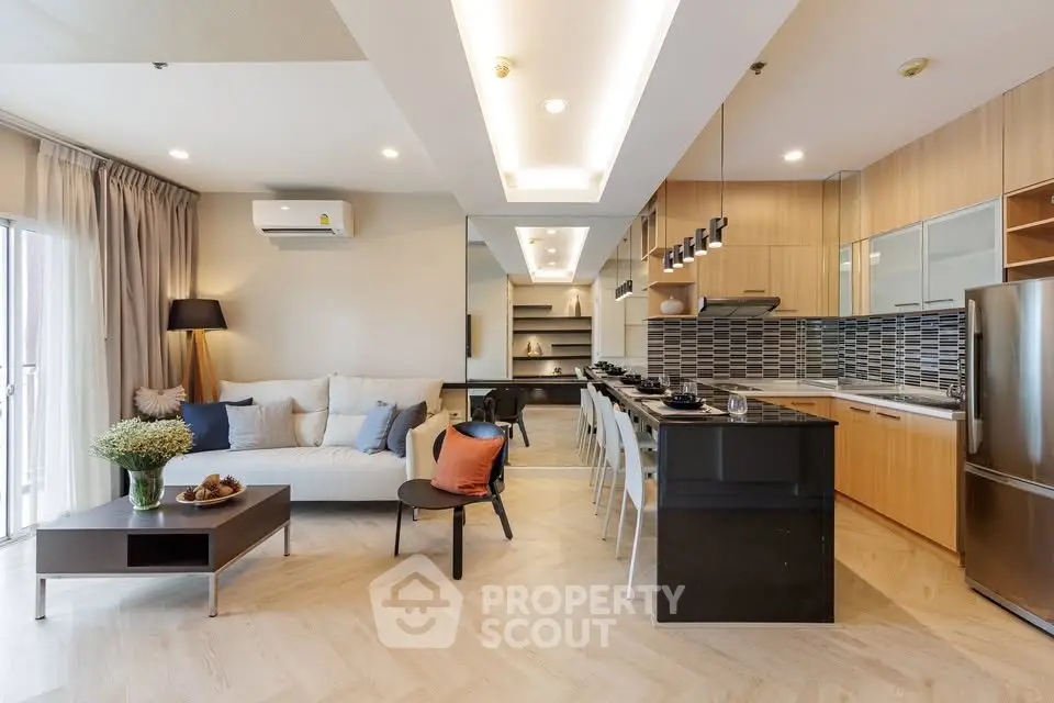 Modern open-layout living room and kitchen with stylish decor and natural light.