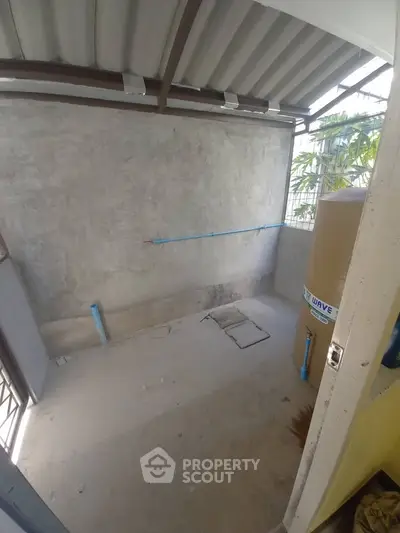 Spacious utility area with concrete walls and water tank, ideal for storage or laundry setup.