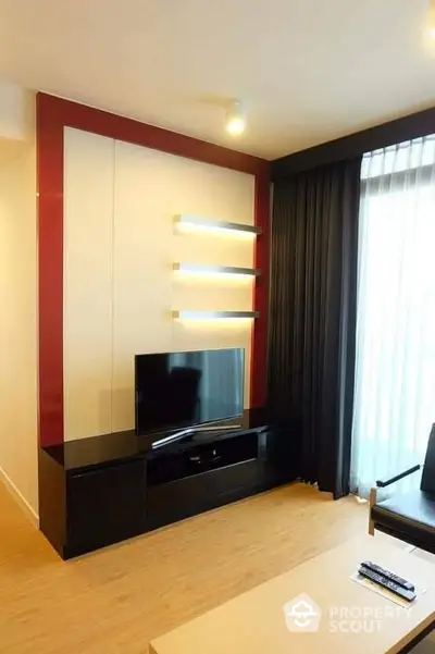 Modern living room with sleek red and white entertainment wall unit, hardwood floors, and elegant black drapes.