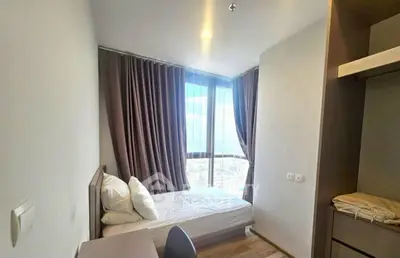Cozy bedroom with large window offering stunning city views, perfect for urban living.