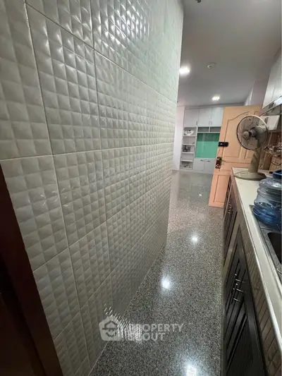 Modern kitchen with sleek cabinets and tiled walls, featuring a spacious layout and contemporary design.