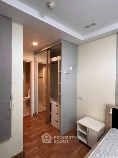 Modern bedroom with ensuite bathroom and walk-in closet, featuring wooden flooring and neutral decor.