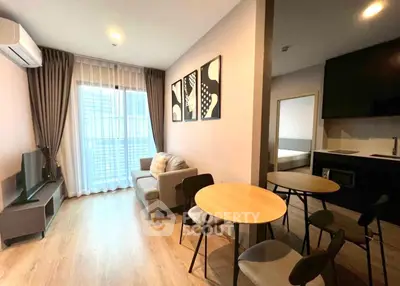 Modern living room with cozy seating and stylish decor, adjacent to a compact kitchen.