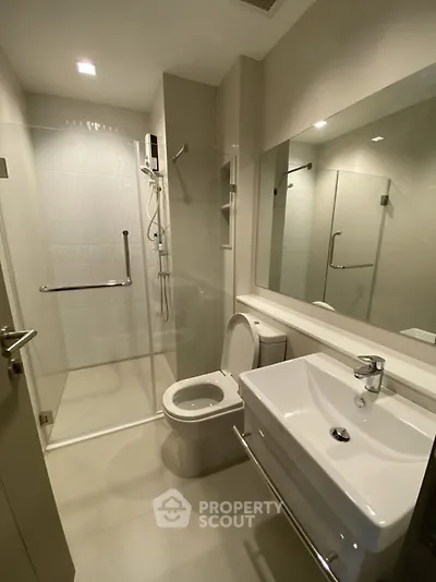Modern bathroom with glass shower enclosure and sleek fixtures in a contemporary apartment.