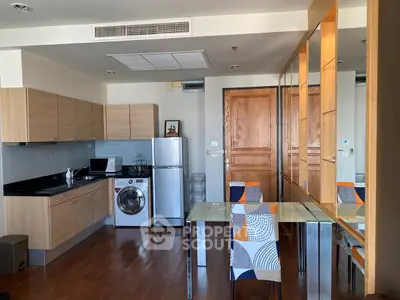 Modern kitchen with wooden cabinets, washing machine, and dining area in open layout apartment.