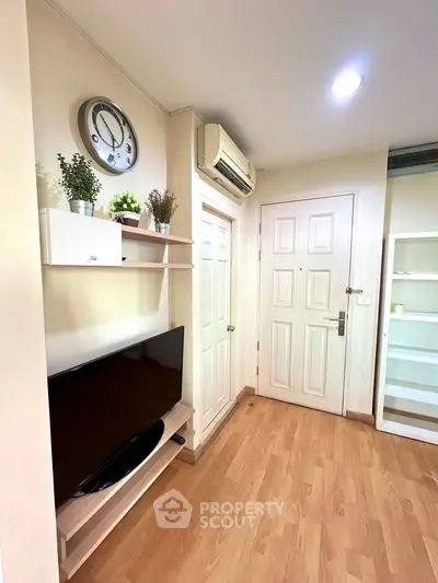 Cozy living room with modern decor, wall-mounted TV, and wooden flooring in a stylish apartment.