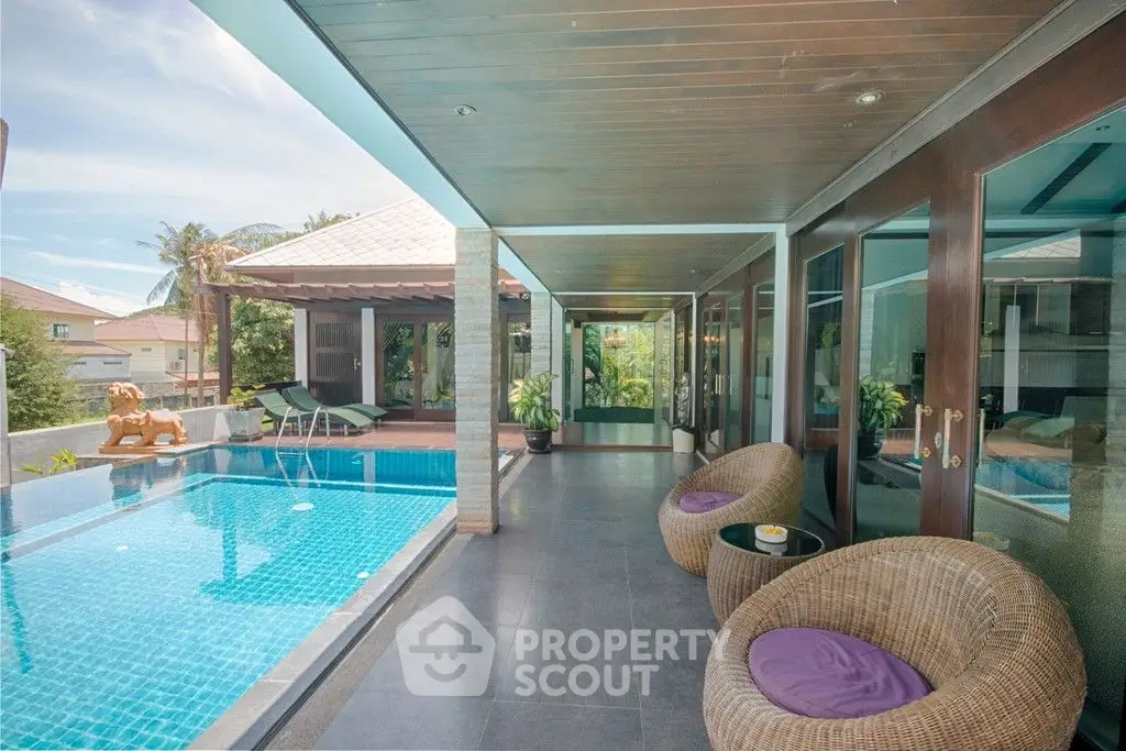 Luxurious poolside patio with modern design and comfortable seating in a tropical villa.