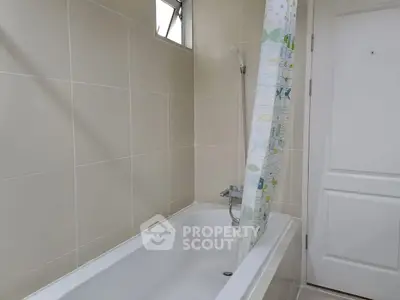 Modern bathroom with sleek bathtub and shower curtain in neutral tones.