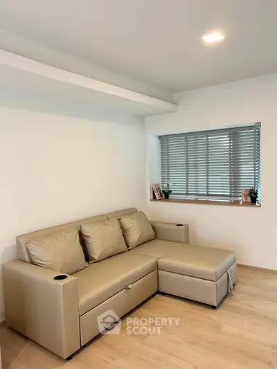 Modern living room with beige sectional sofa and window blinds, perfect for cozy relaxation.