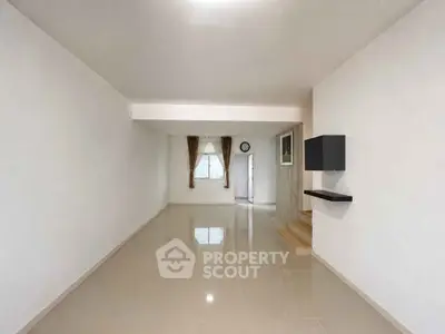 Spacious minimalist living room with glossy tiled floors and neutral walls, perfect for modern living.