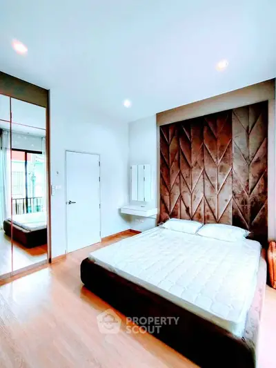 Modern bedroom with stylish headboard and mirrored closet in bright apartment